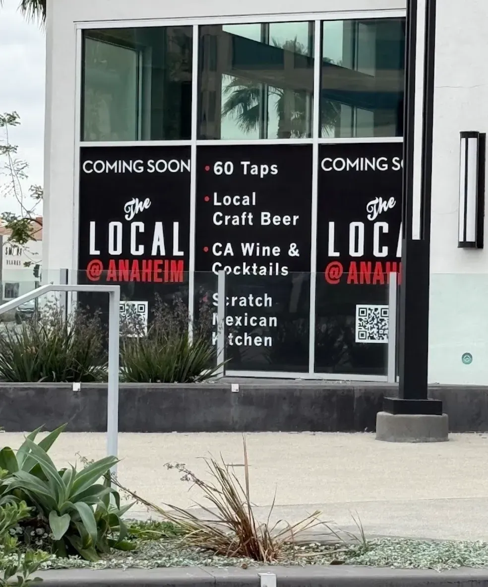 Storefront window signs reading “Coming Soon,” “The Local,” and menu items in black and white.