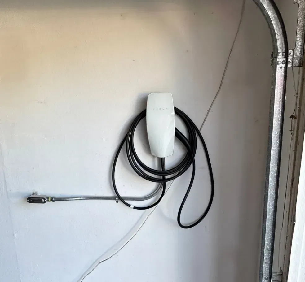 Coiled black hose and white wall-mounted fixture in a garage with exposed conduit