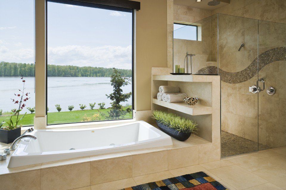 Bagno con ampia finestra con vista sul lago, vasca, doccia e mensole integrate. Pareti beige e luce naturale.