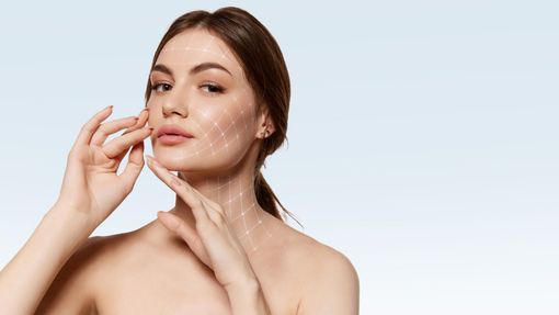 Woman applying facial cream against a light background. Woman applying facial cream against a light background.
