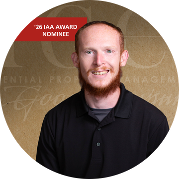 Man with red beard smiles, wearing a black shirt, in front of a golden background with text.