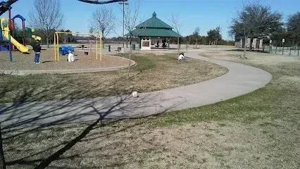 Burleson Electrician - Sunny park scene with a winding path, a playground to the left with children playing, a gazebo in the background, and leafless trees throughout.