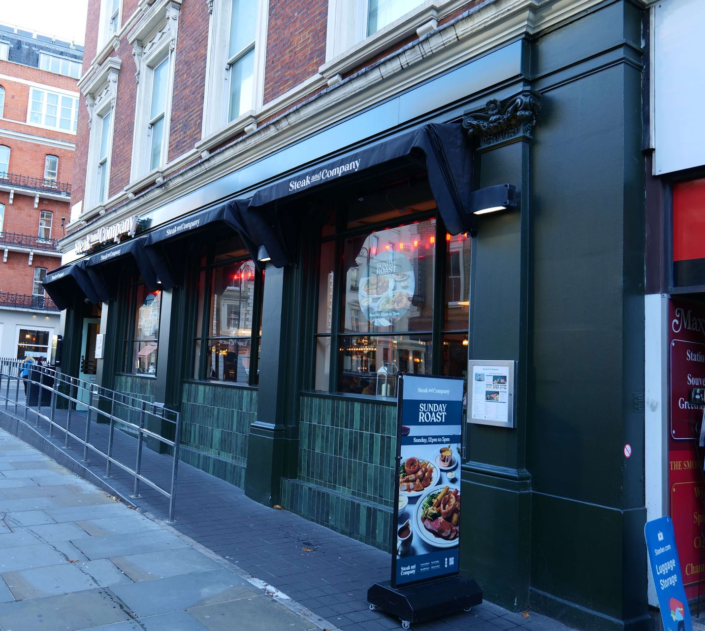 Steak and Company restaurant exterior. Green facade, awnings, windows, brick building.