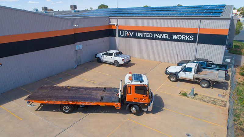 A flatbed tow truck and several pickup trucks parked at the 