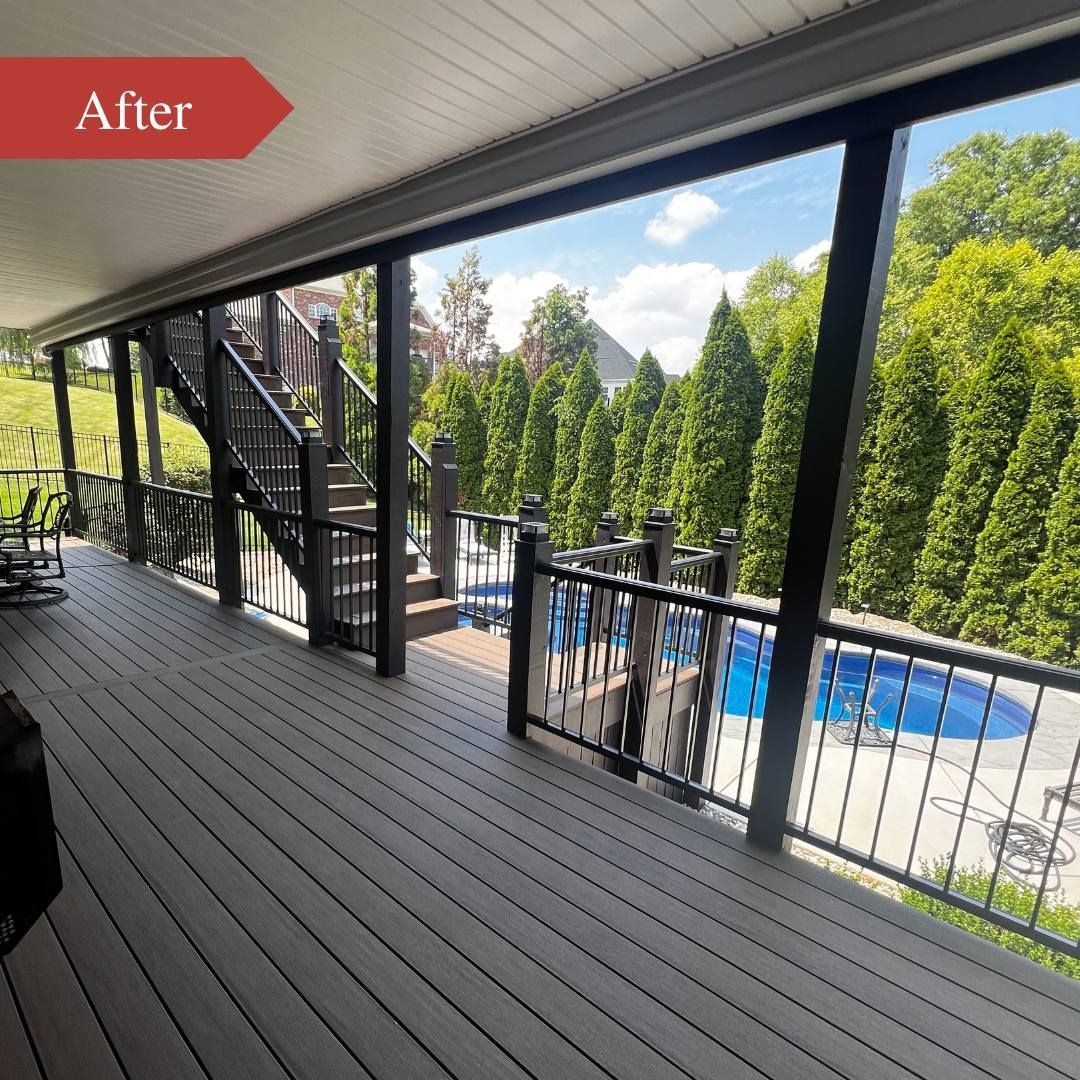 Covered deck overlooking a backyard pool, with gray flooring, black railings, and tall green hedges.