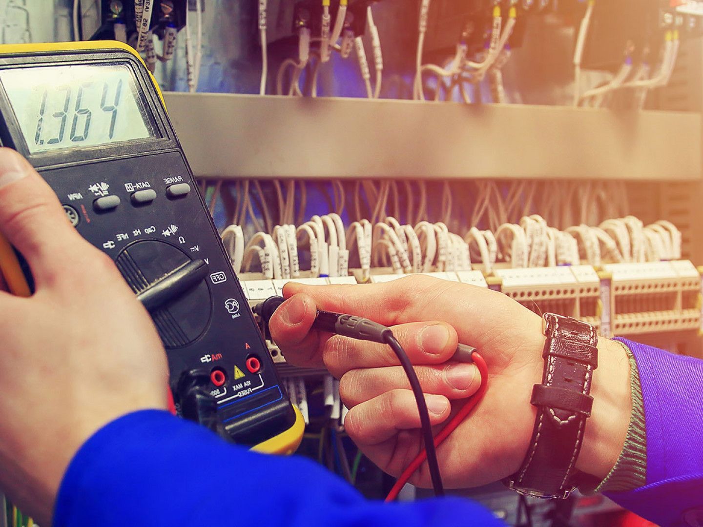 A man is using a multimeter to test a circuit board.