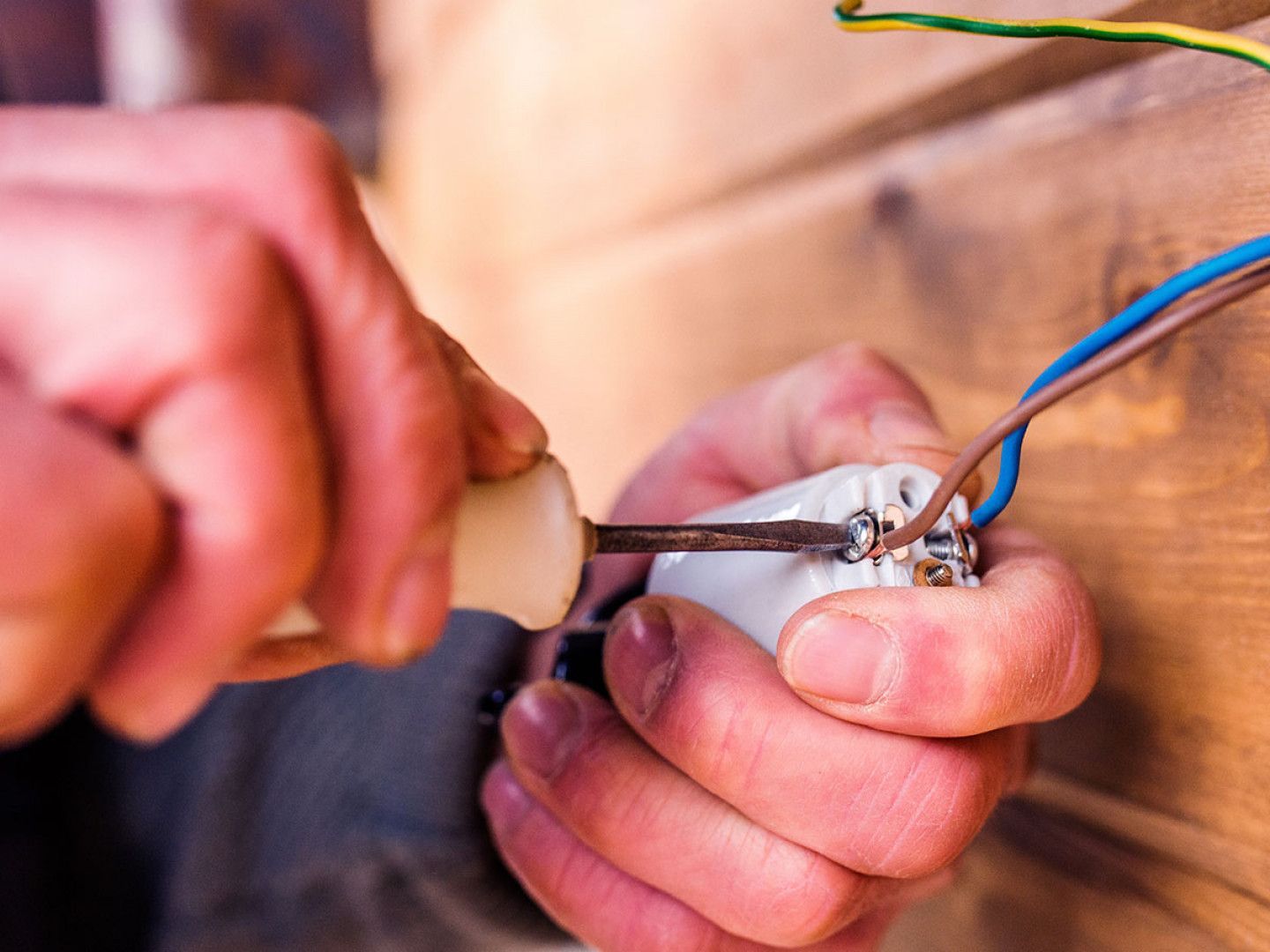 A person is holding a screwdriver and a light bulb in their hands.