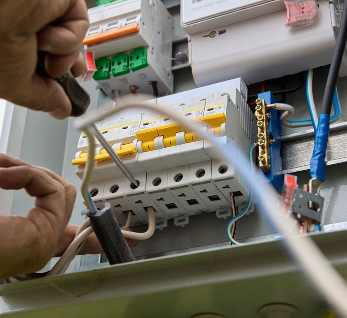 A person is working on an electrical box with a screwdriver