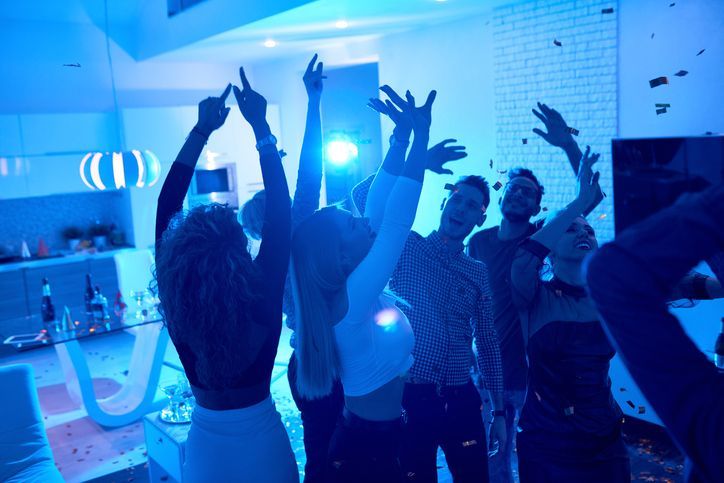 A group of people are dancing in a room with blue lights.