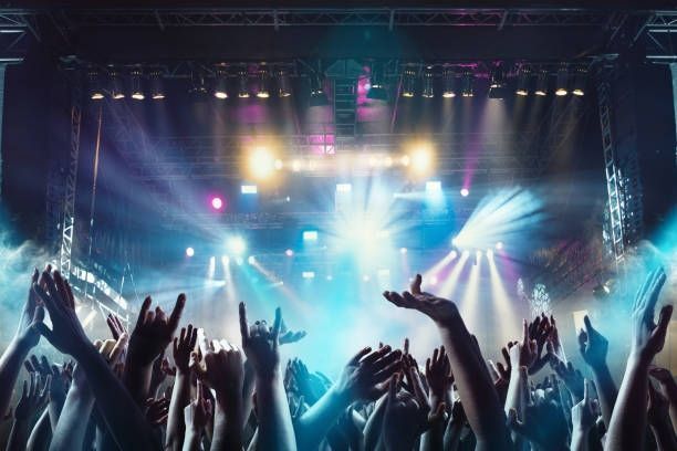 A crowd of people are raising their hands in the air at a concert.