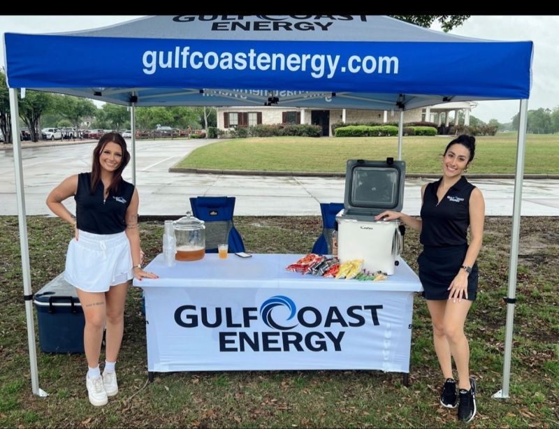 Two women standing in front of a gulfcoast energy tent