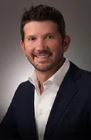 A man in a suit and white shirt is smiling for the camera.