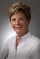 A woman in a white shirt is smiling for the camera.