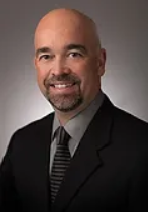 A man in a suit and tie is smiling for the camera.