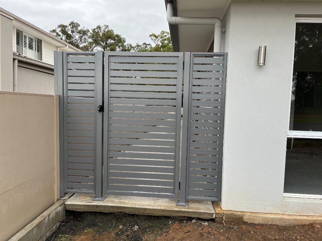 A Gray Gate is Sitting in Front of a  White House — Newcastle & MidCoast Privacy Screens & Gates In Kurri Kurri, NSW