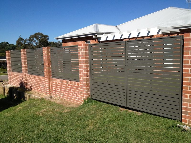 A Brick Wall With A Metal Fence Surrounding It — Newcastle & MidCoast Privacy Screens & Gates In Maitland, NSW