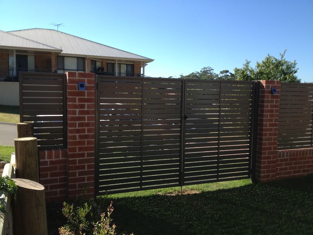 A Brick Wall and Black Metal Fence — Newcastle & MidCoast Privacy Screens and Gates In Kurri Kurri, NSW