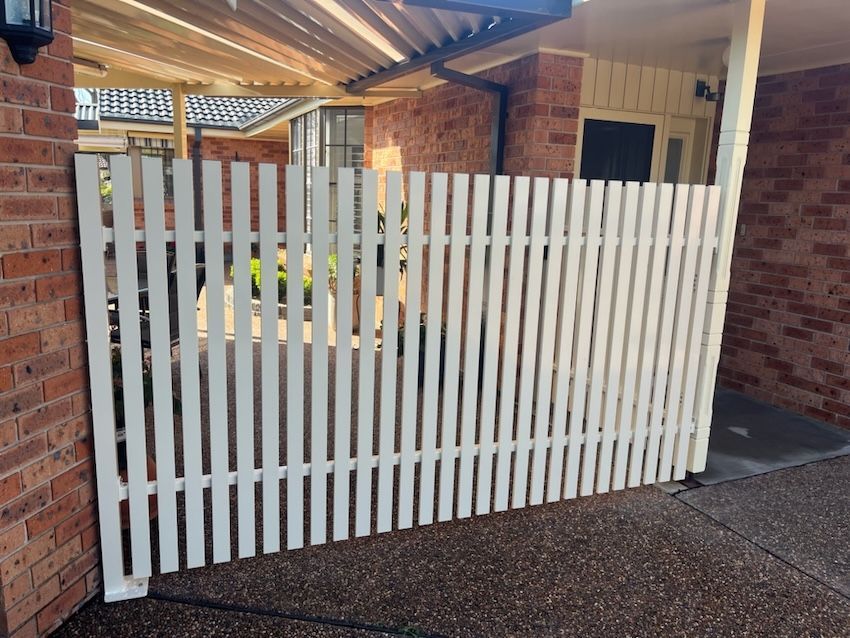 A White Picket Fence next to a Brick House — Newcastle & MidCoast Privacy Screens and Gates In Mid North Coast, NSW