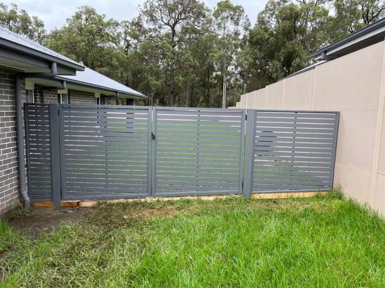 A Fence With a Gate in the Backyard of a House — Newcastle & MidCoast Privacy Screens and Gates In Kurri Kurri, NSW