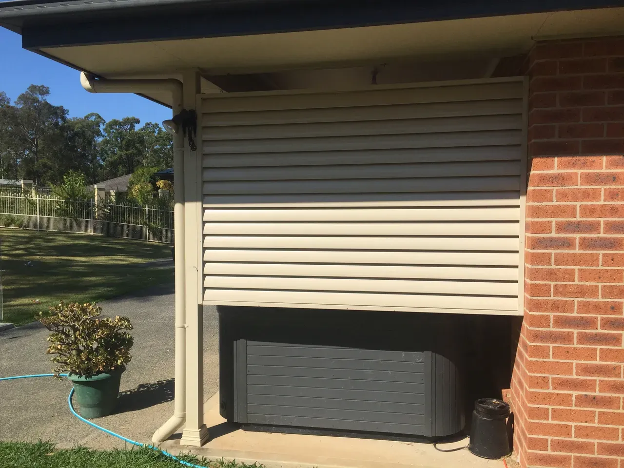 A Hot Tub Is Sitting Under A Shutter On The Side Of A House — Newcastle & MidCoast Privacy Screens & Gates In Newcastle, NSW