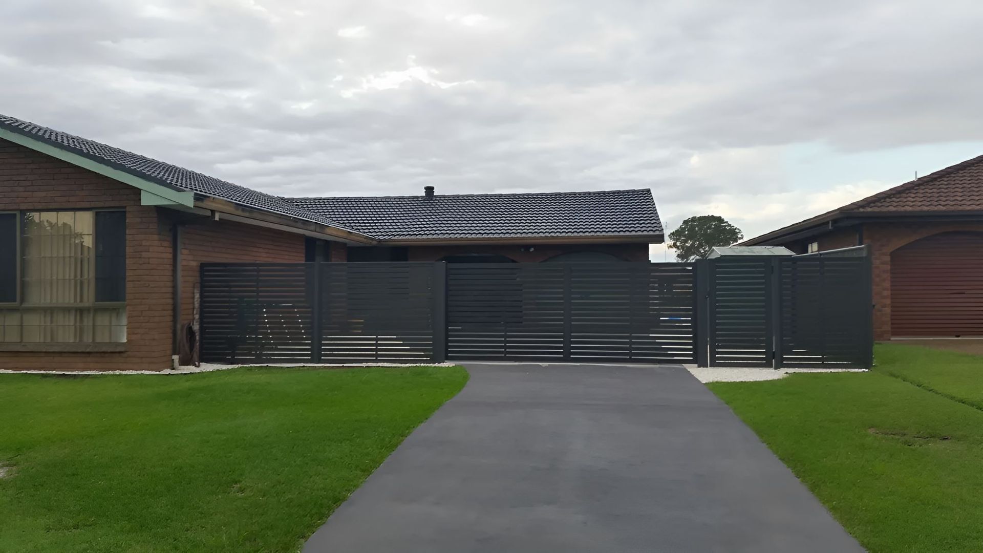 A Driveway Leading To A House With A Black Gate — Newcastle & MidCoast Privacy Screens & Gates In Newcastle, NSW