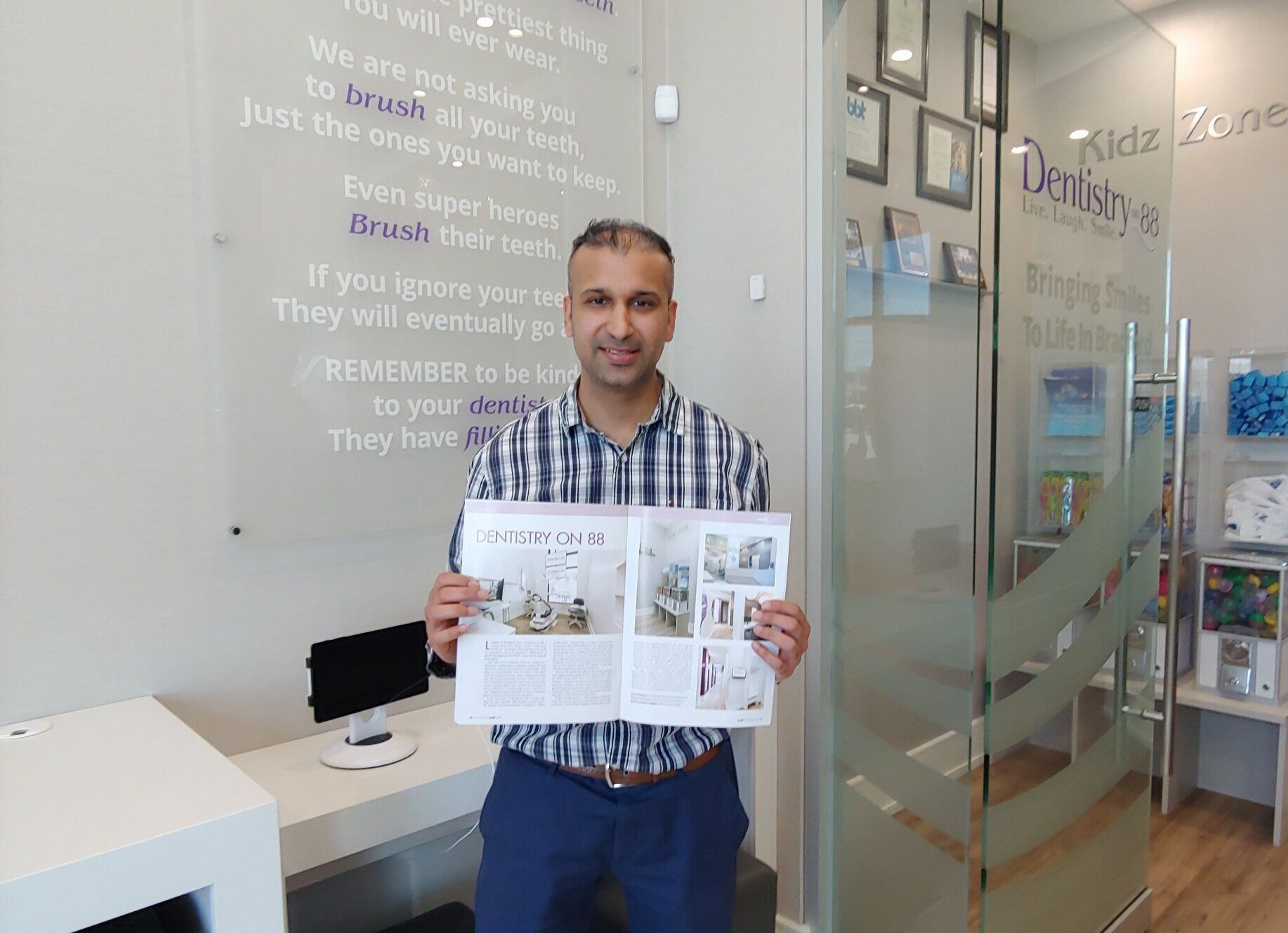 Man holding an open newspaper in a bright office lobby beside a glass door