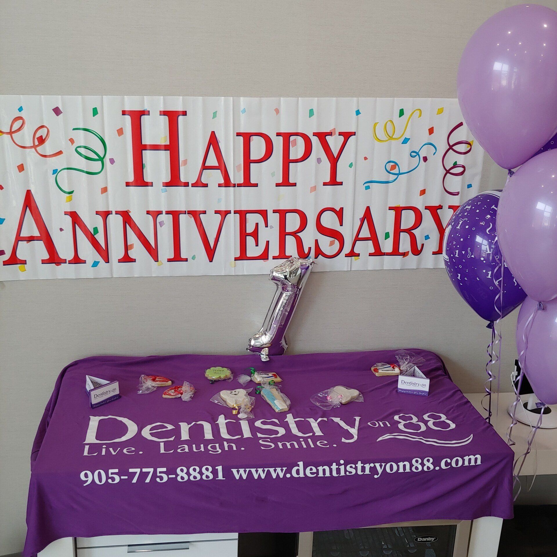 Happy anniversary banner with purple balloons and a Dentistry table display