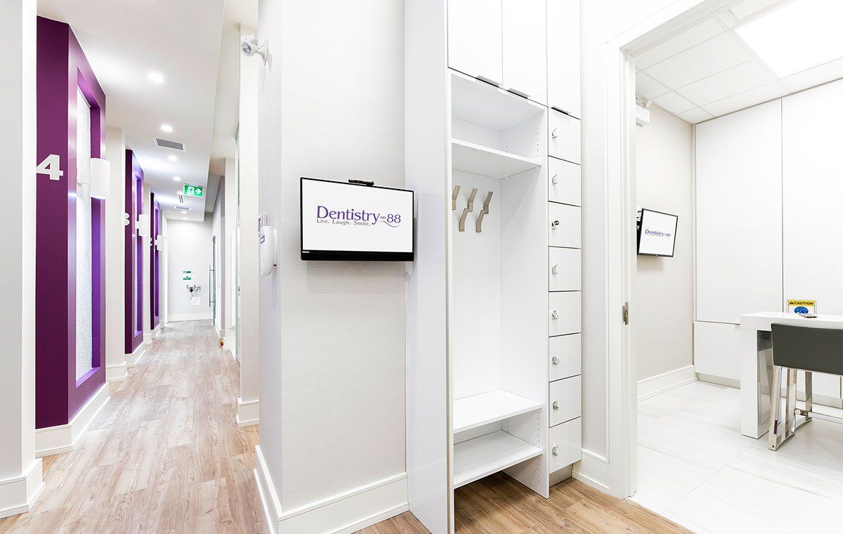 Bright hallway with purple doors, white walls, wood floor, and an open white closet area