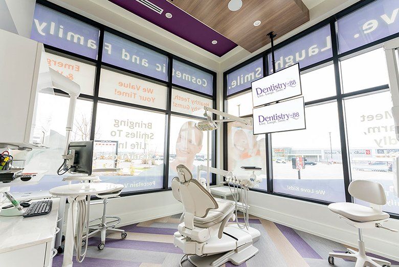 Modern dental office interior with reclining chair, desk, and large windows with frosted signage