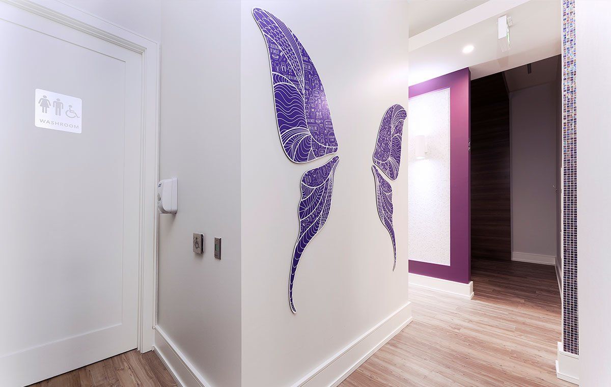 Bright hallway with purple wall art, white doors, and wood flooring.