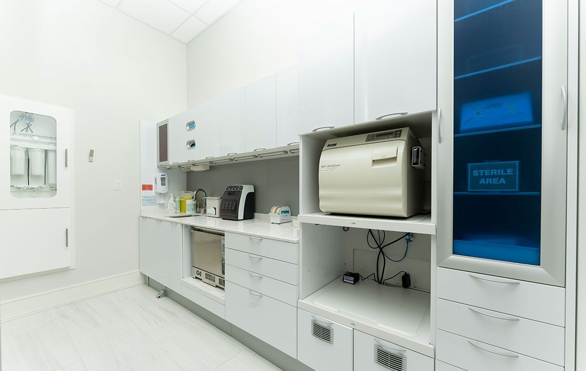 Bright hospital room with white cabinets, medical equipment, and a small window with blue light.