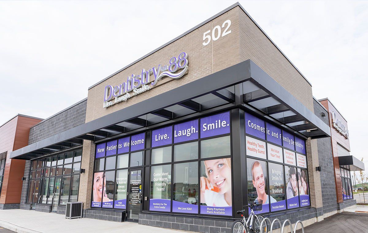 Exterior of a dental clinic storefront with purple signage and large windows, building number 502 visible
