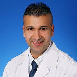 Portrait of a smiling doctor in a white coat against a blue background