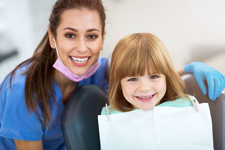 Dentist with smiling child in a clinic, wearing blue gloves and holding a dental bib