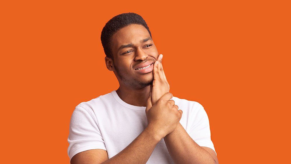 Person smiling with hands clasped against a bright orange background
