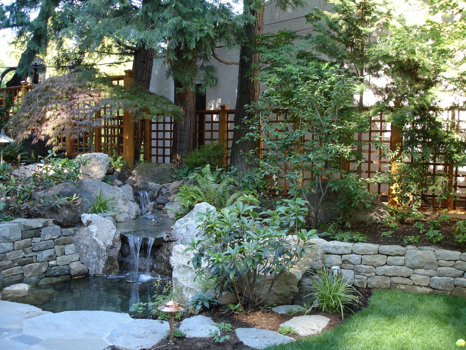 A garden with a waterfall and a stone wall