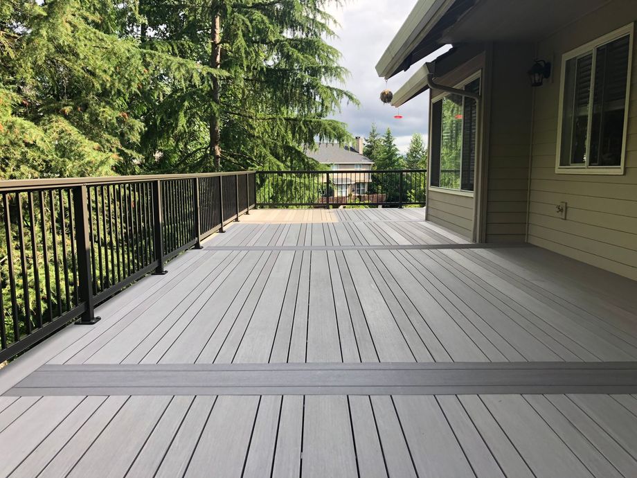 A large deck with a railing and trees in the background