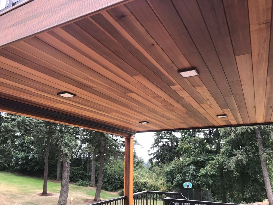 A deck with a wooden ceiling and trees in the background