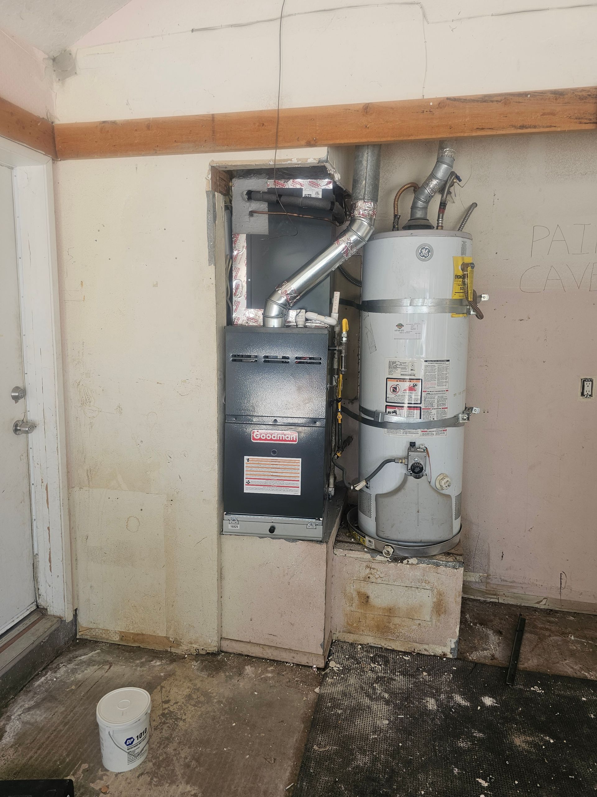 Utility room with furnace and water heater beside a wall, with debris on the floor.