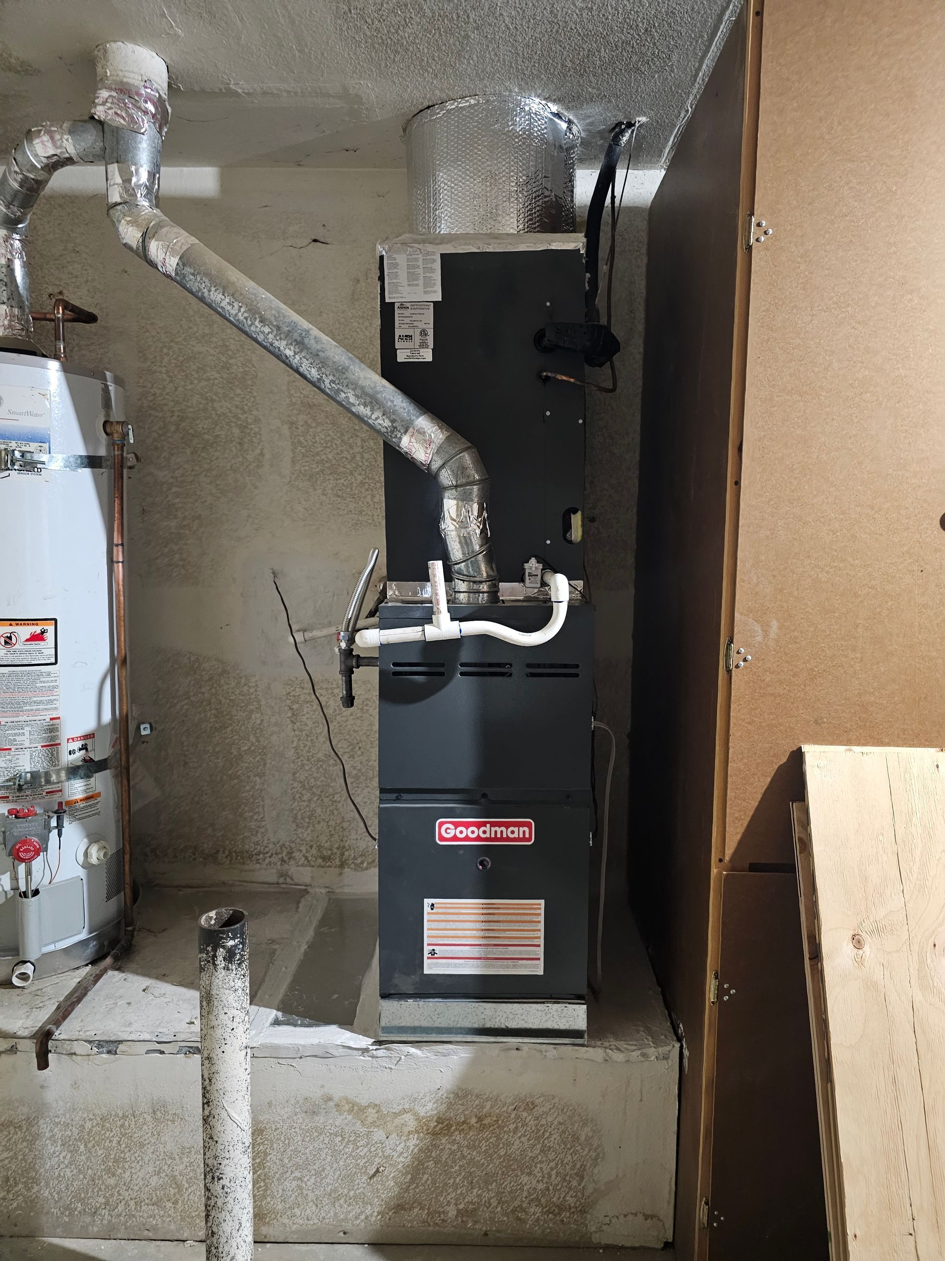 HVAC furnace and ductwork in a utility closet, with exposed insulation and pipes