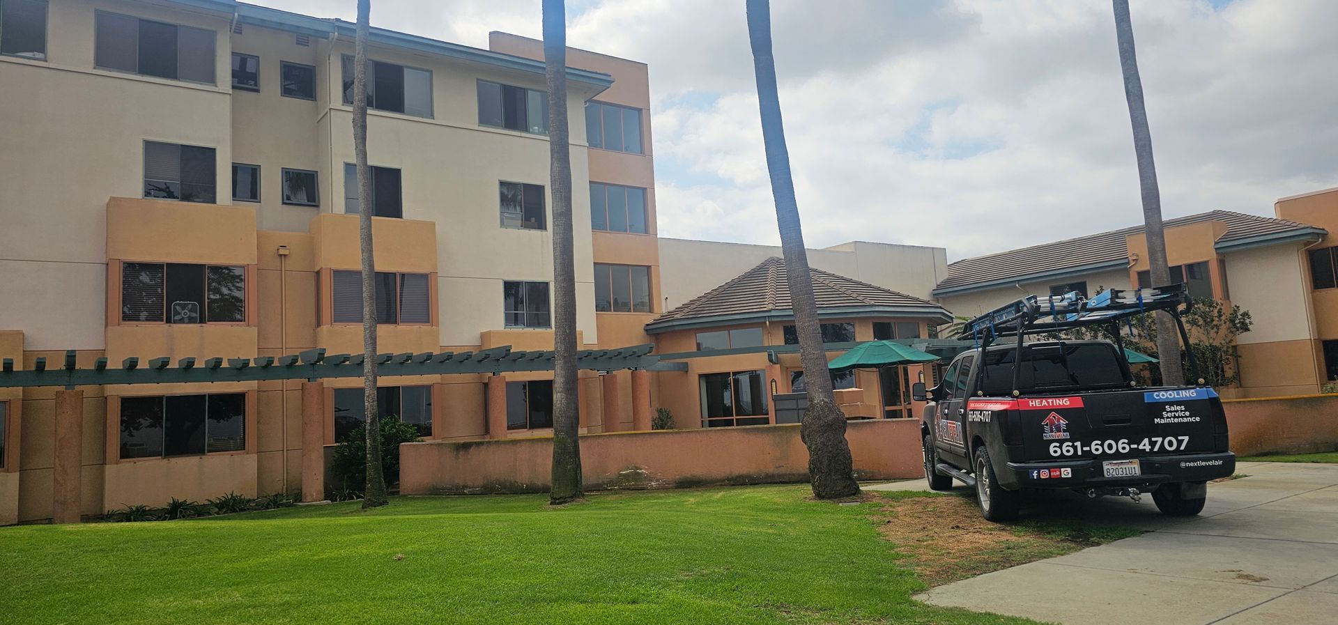 Multi-story beige building with green lawn and a black police SUV parked outside
