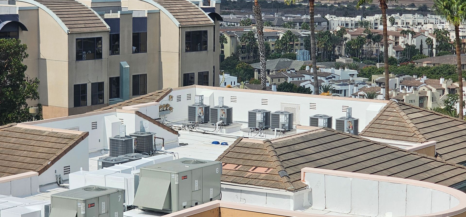 Apartment rooftops with HVAC units and tan buildings overlooking a marina and cityscape