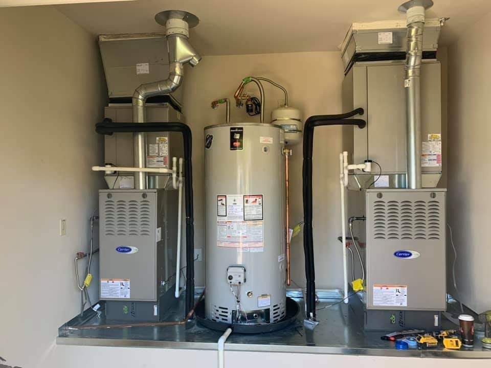 Three HVAC units and a water heater in a small utility closet