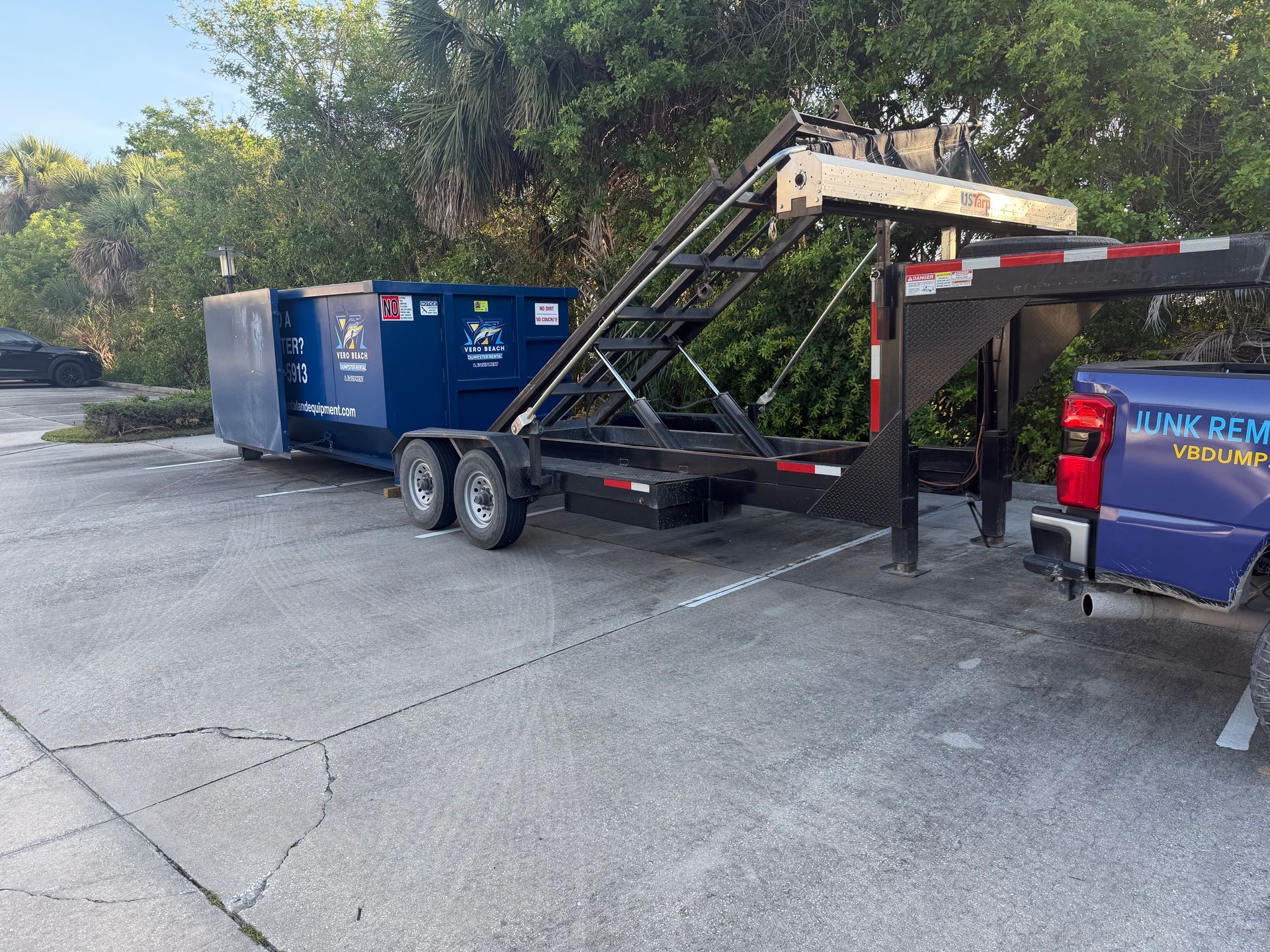 Black dumpster with company logo and phone number, likely used for waste disposal.