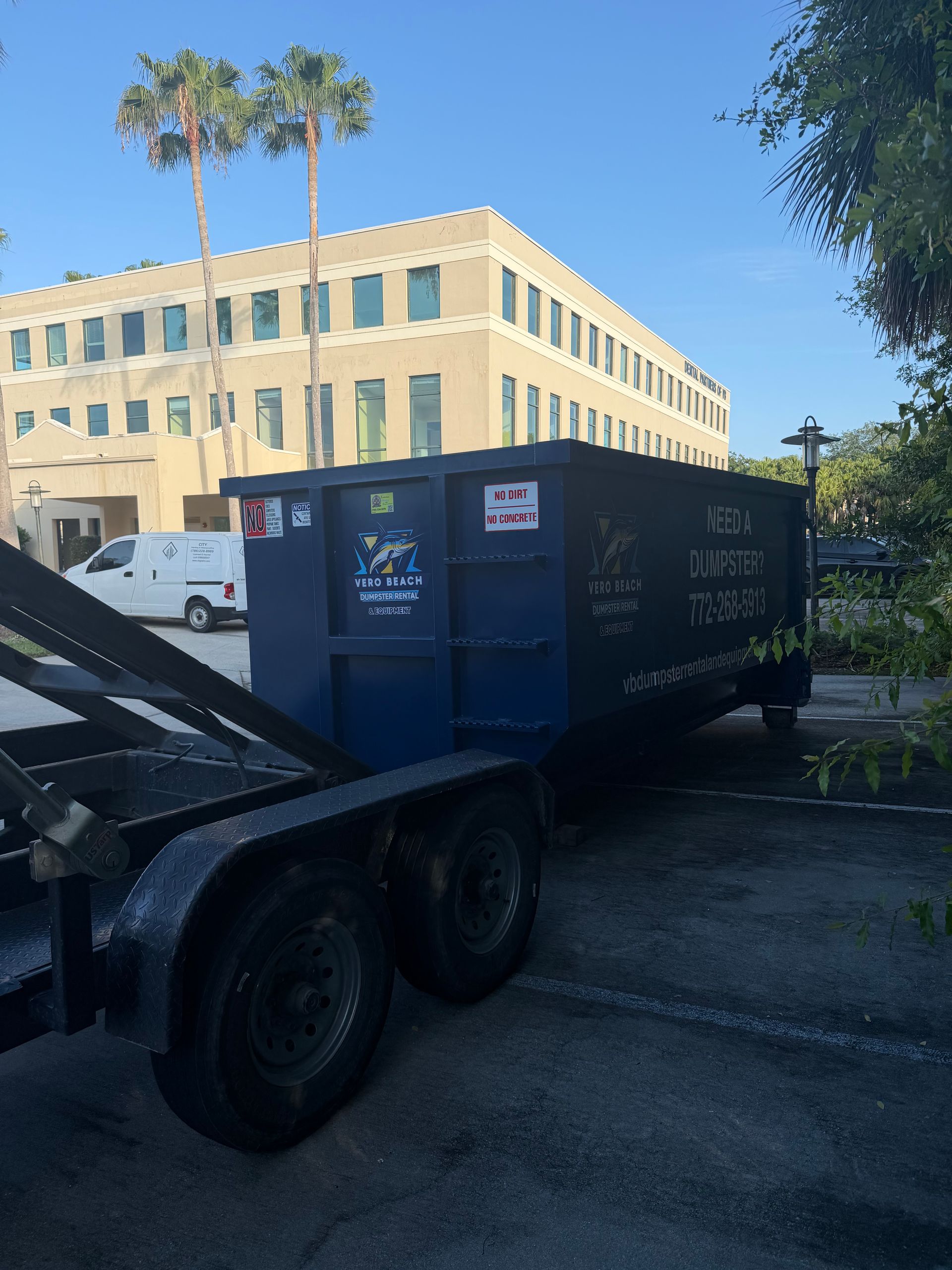 Black dumpster with company logo and phone number, likely used for waste disposal.