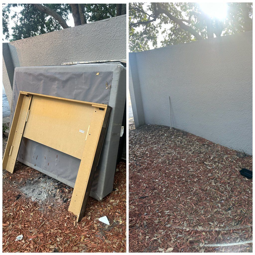 Discarded framed board and covered object leaning against a stucco wall in a leaf-covered yard.