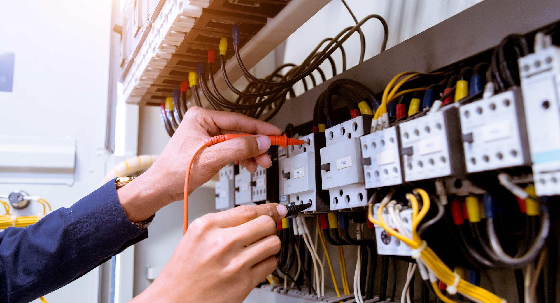 A person is working on an electrical panel with a screwdriver.