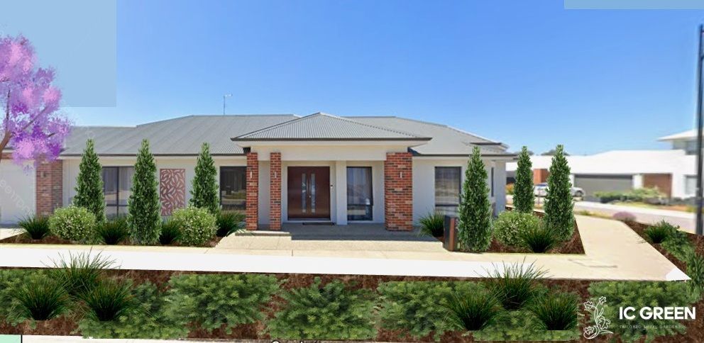 A house with a grey roof and brick columns has a landscaped front yard with green bushes and trees.