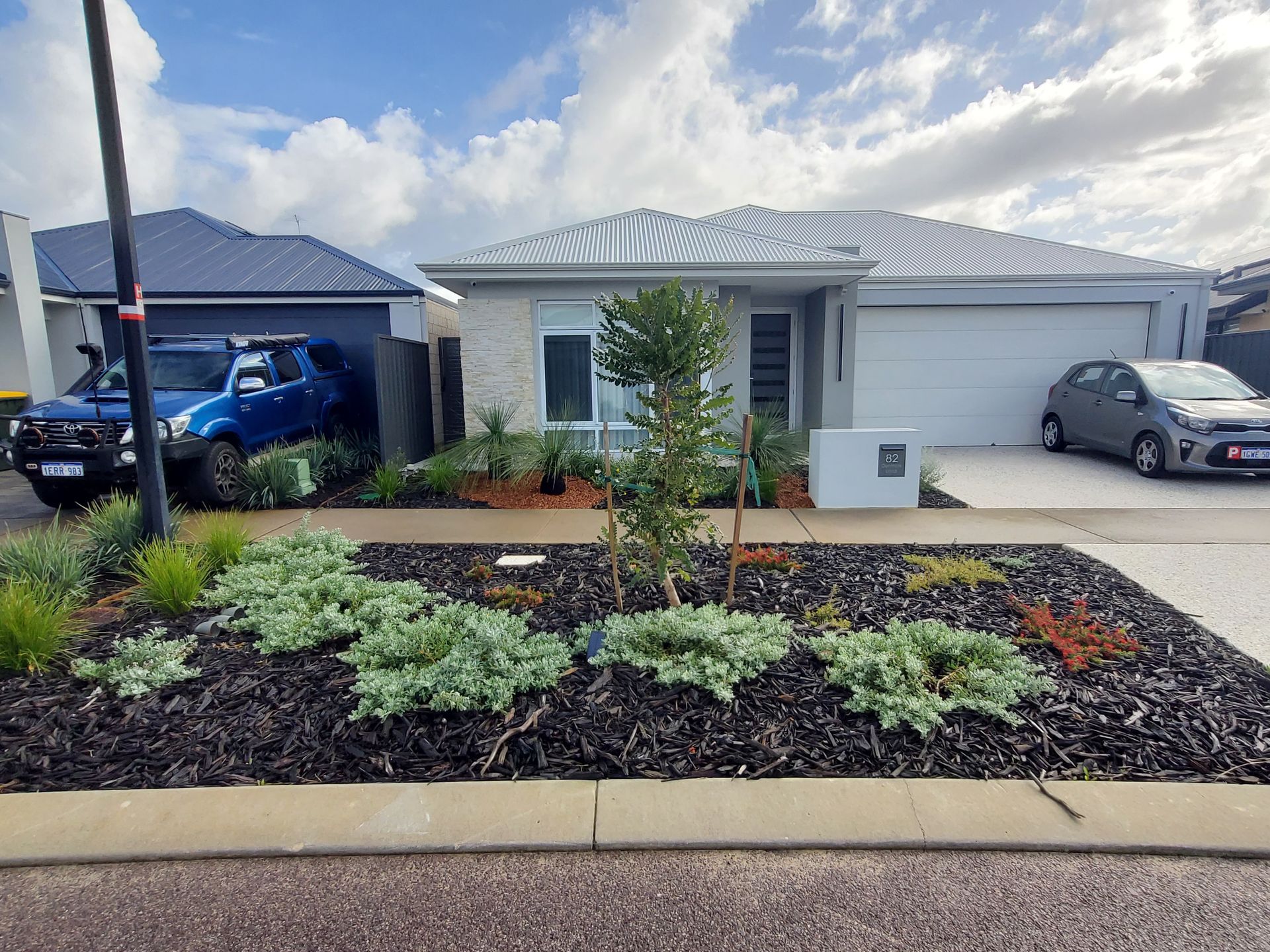 A modern house with a gray garage, a landscaped front yard, and two parked cars.