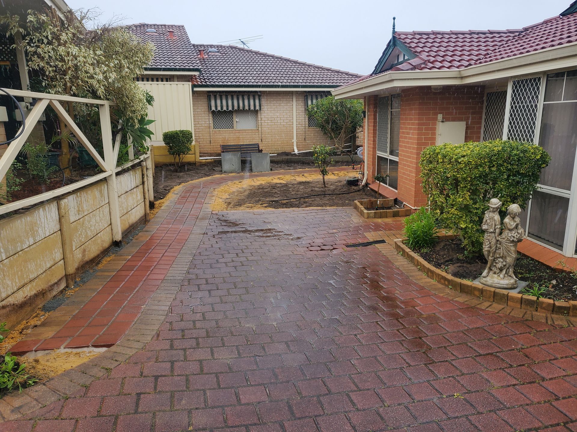 Brick driveway leading to houses on a rainy day.